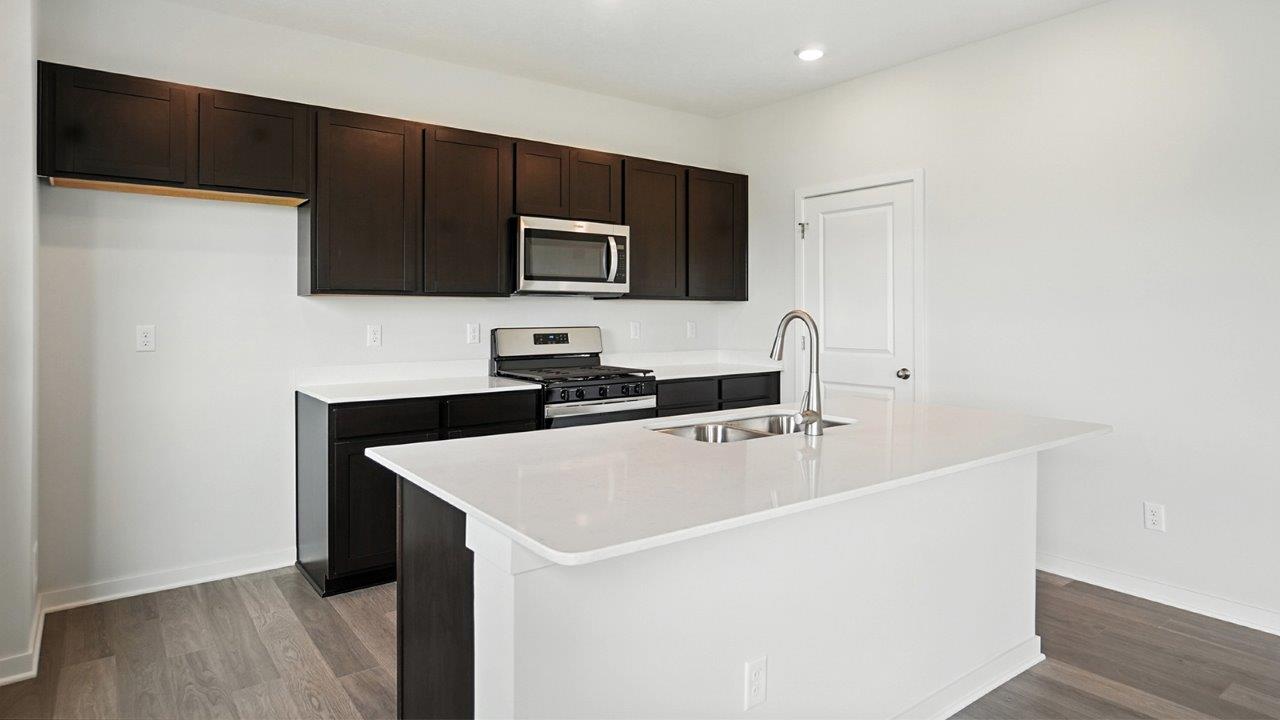 kitchen with brown cabinets, built in island, stainless steel appliances, walk in pantry