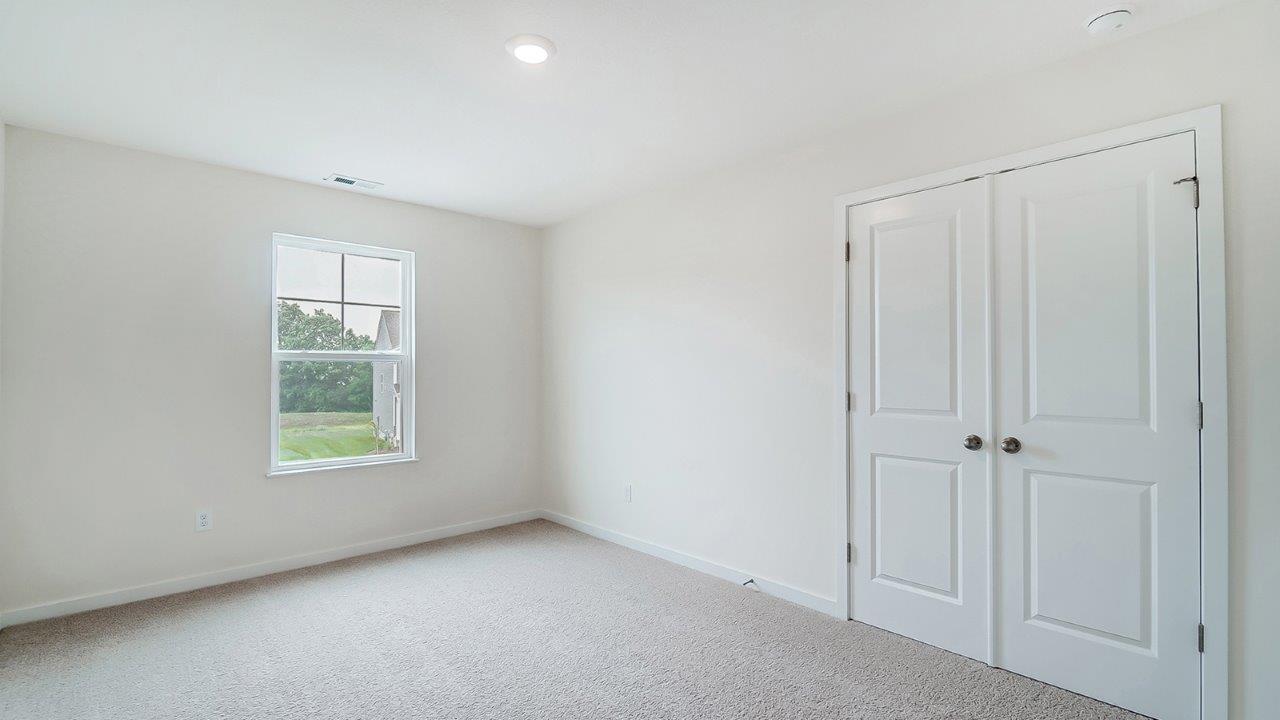 bedroom with beige carpet, white walls and a window