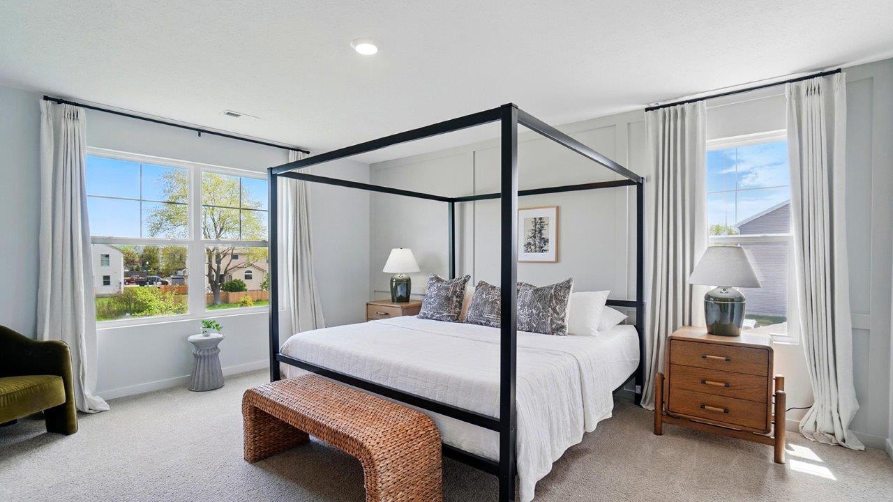 primary bedroom featuring a black steel bed with brown nighstands on either side of the bed with 2 large windows