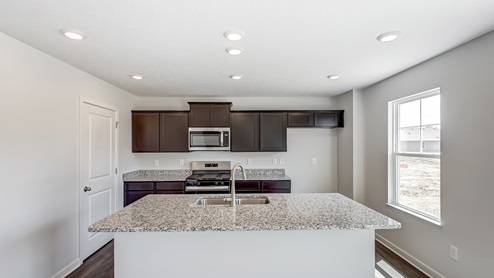 kitchen with brown cabinets, built in island, stainless steel appliances and walk in pantry