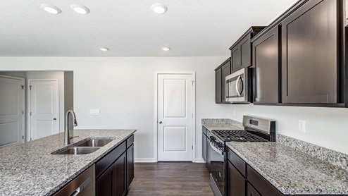 brown kitchen cabinets, hard surface counters, built in island, walk in closet and stainless steel appliances