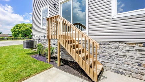 2 story home with grey siding steps to grade