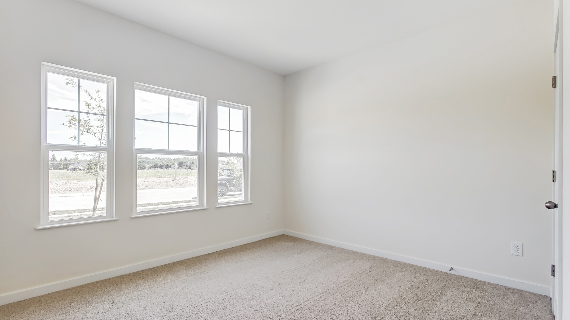 Bedroom with neutral walls, carpet, and a window.