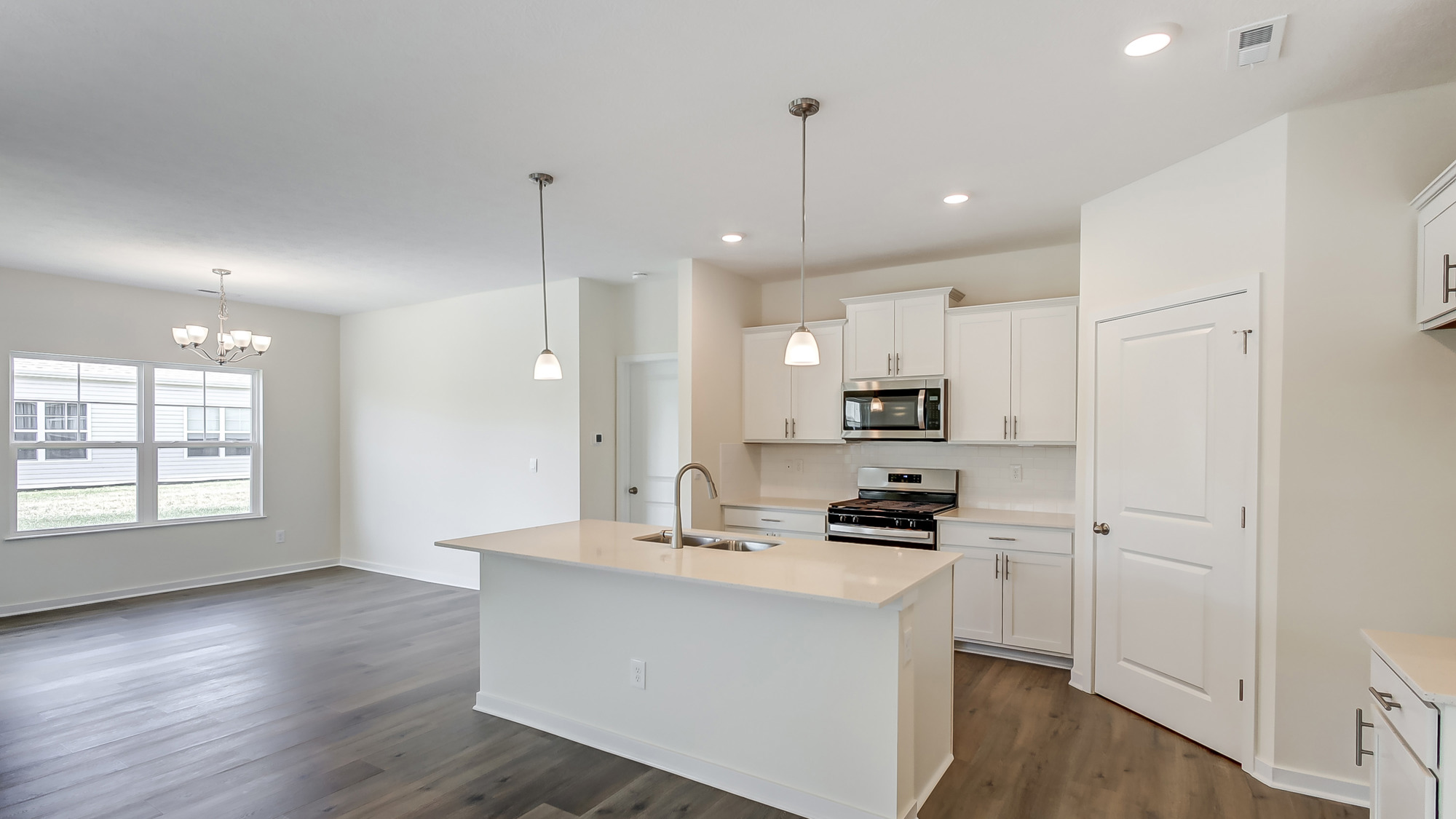 Kitchen featuring cabinets, new stainless steel appliances, and large countertops connecting to dining area.