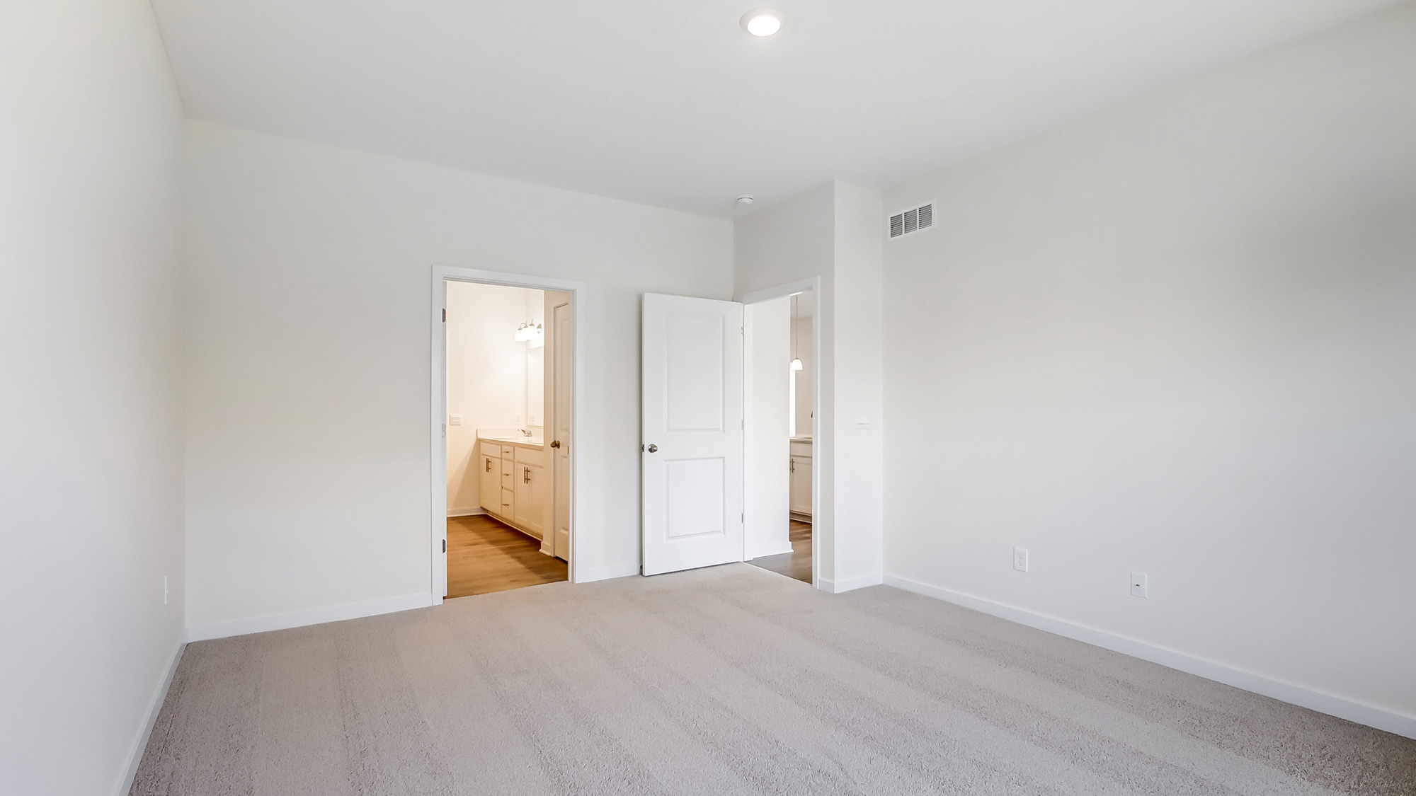 Primary bedroom with carpet, natural lighting, and a bathroom attached.