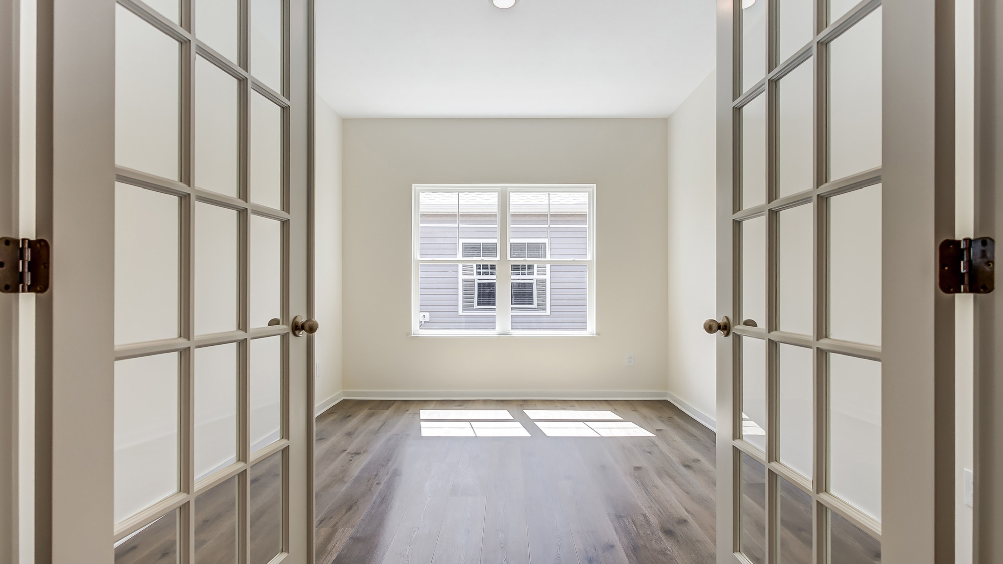 Room with neutral floors, natural light, and double doors.
