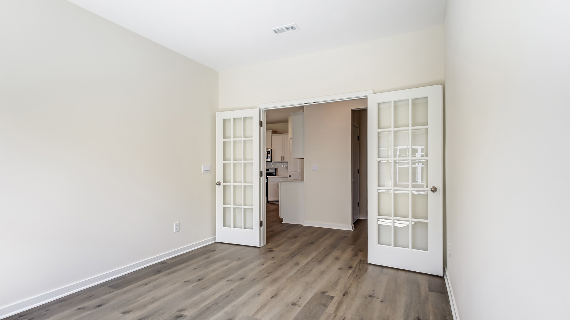 Room with neutral floors, natural light, and double doors.