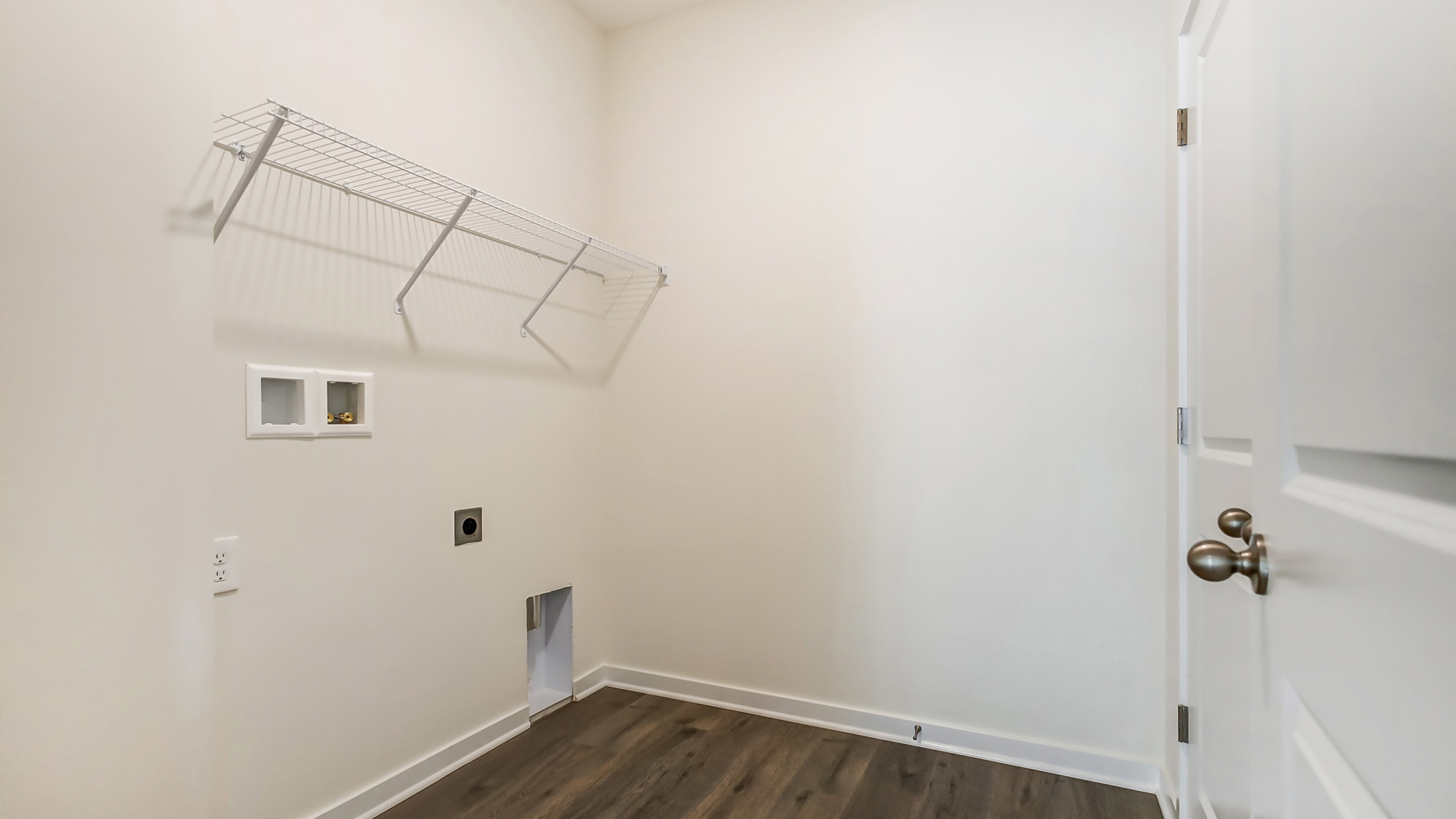 Laundry room with shelving above appliance hook ups.