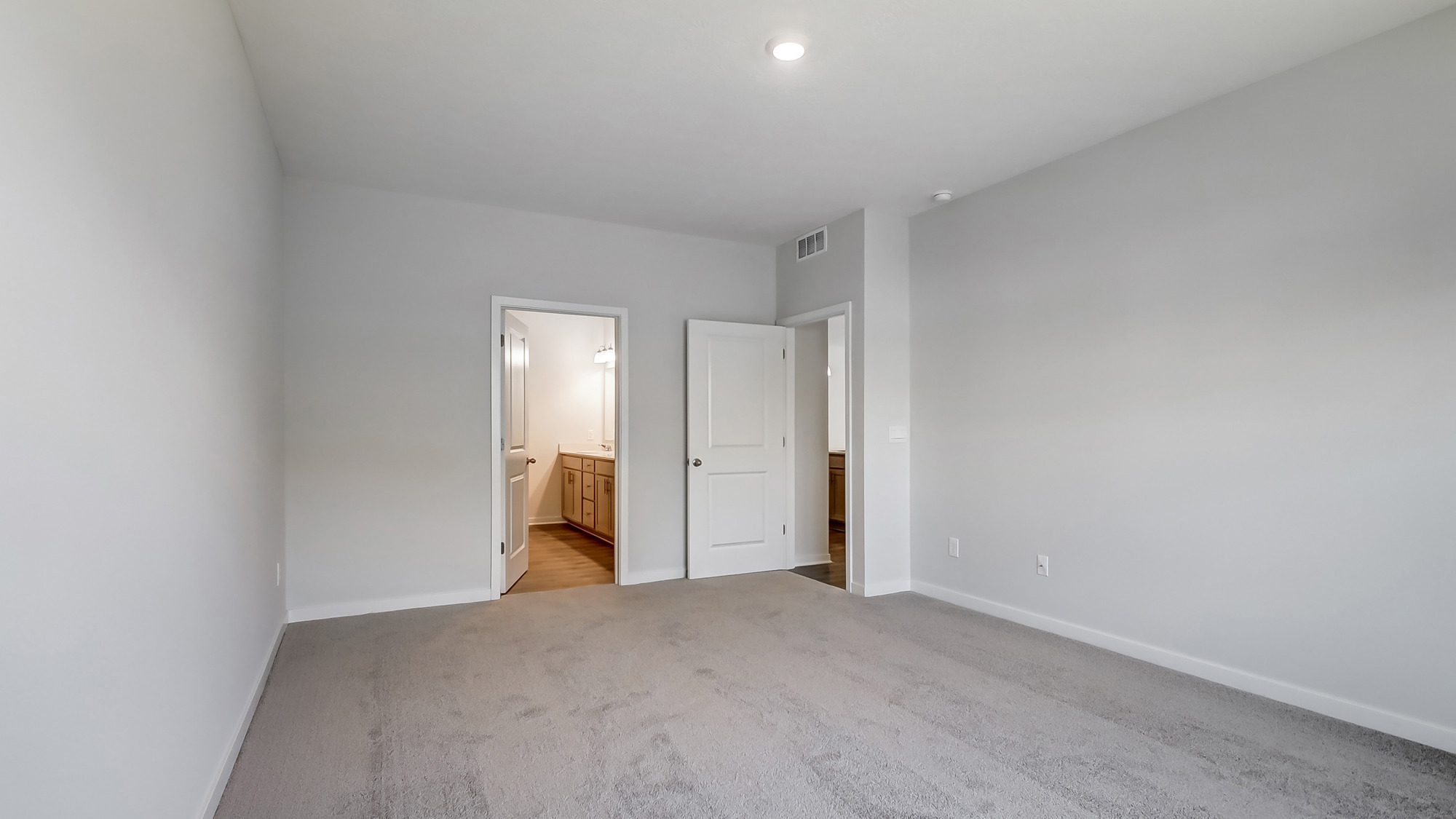 Primary bedroom with carpet, natural lighting, and a bathroom attached.