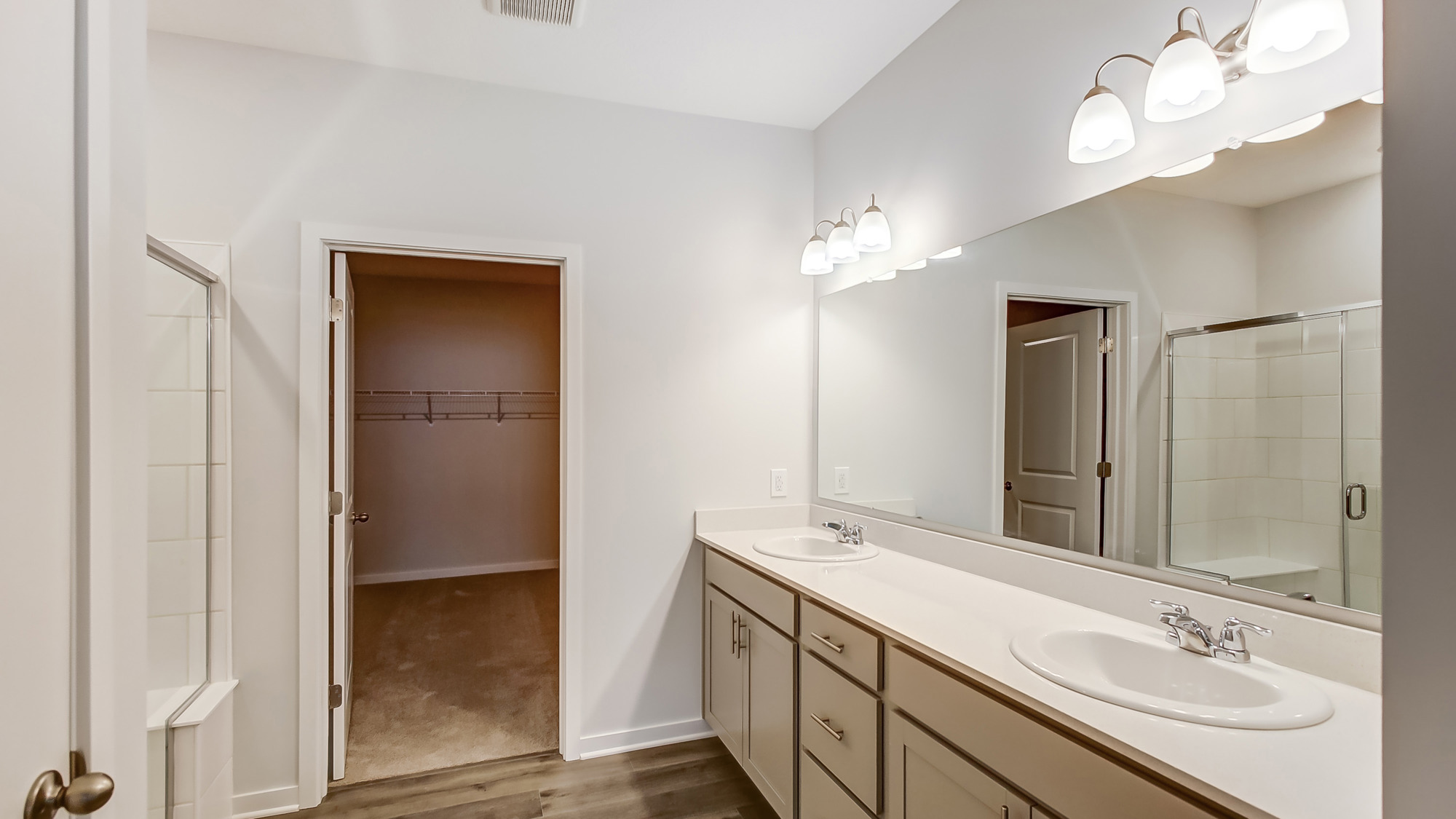 Bathroom with dual sinks and a walk in closet.