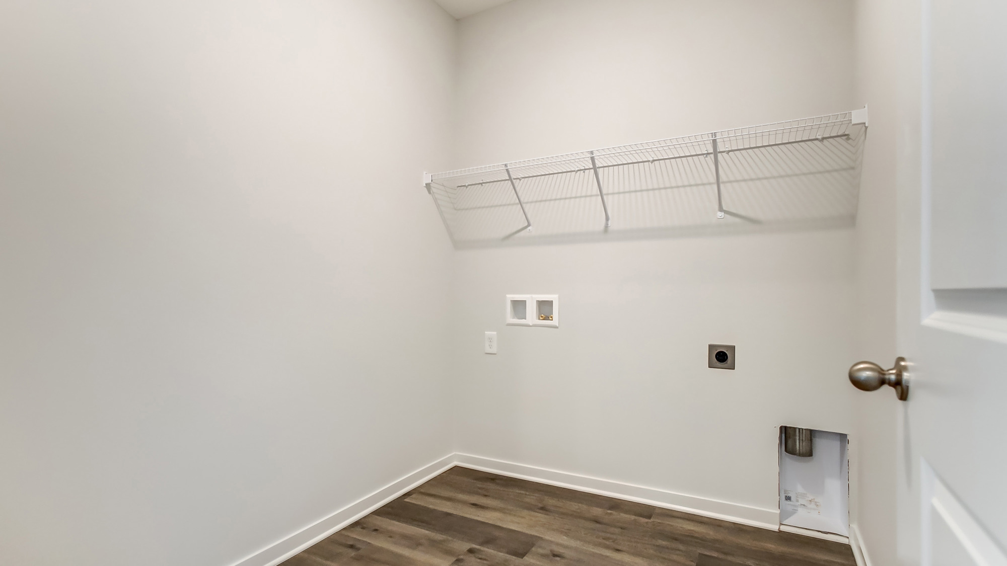 Laundry room with shelving above appliance hook ups.