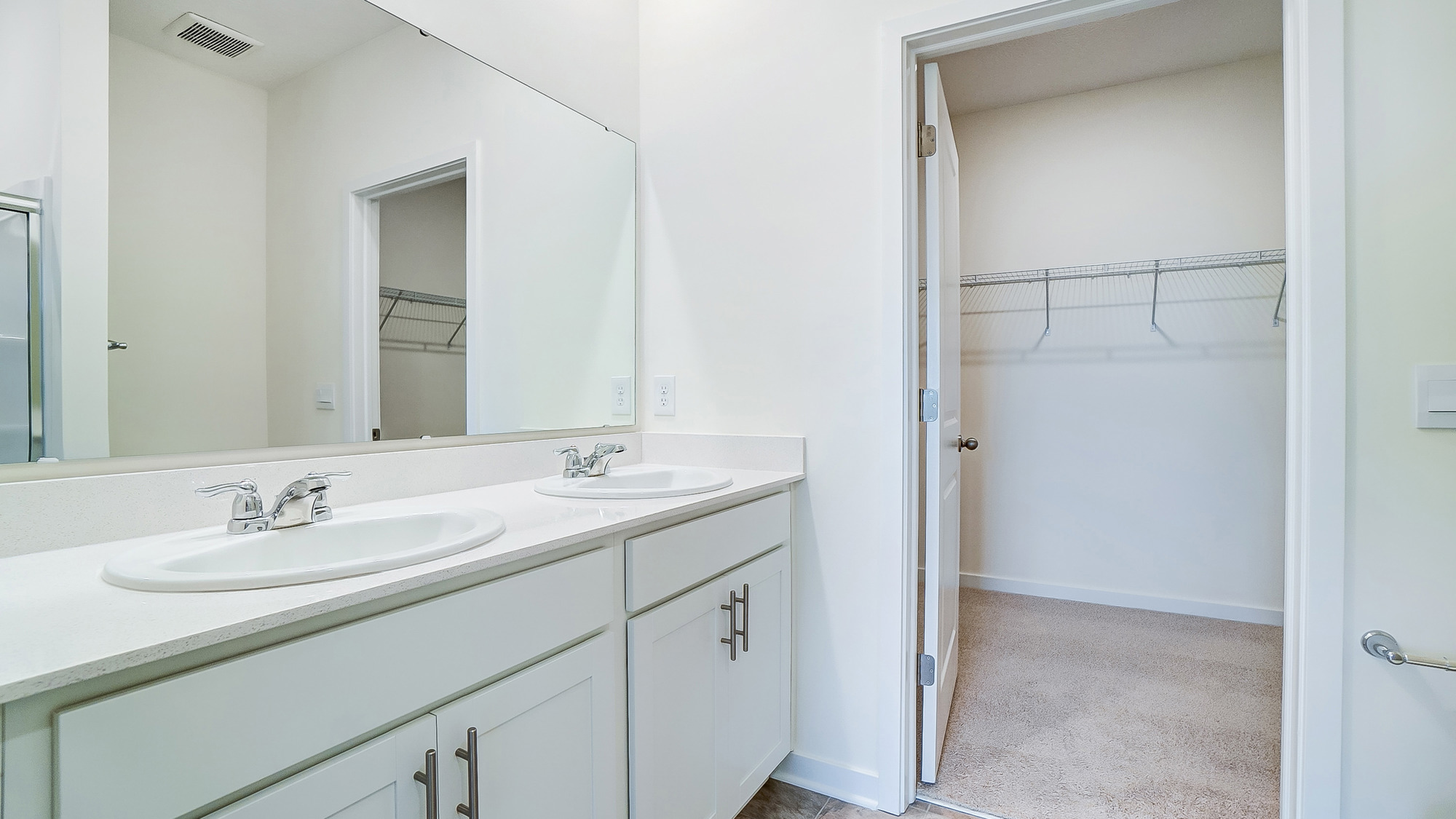 Bathroom with dual sinks and a walk in closet.