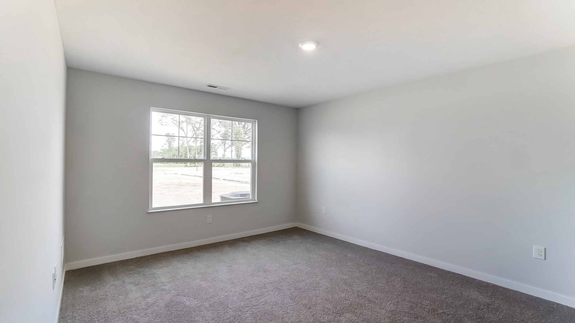 Primary bedroom with large windows and neutral walls.