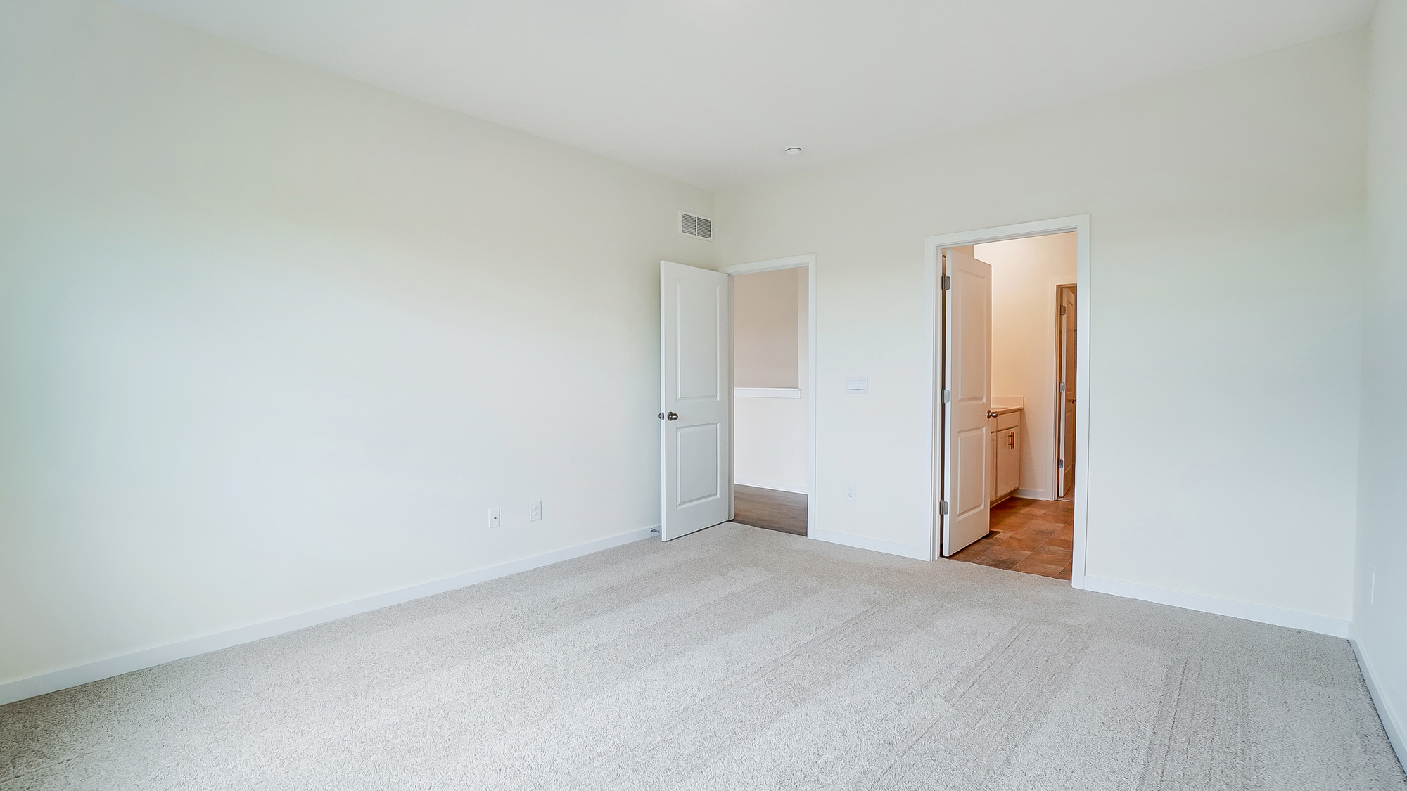 Primary bedroom with carpet, natural lighting, and a bathroom attached.
