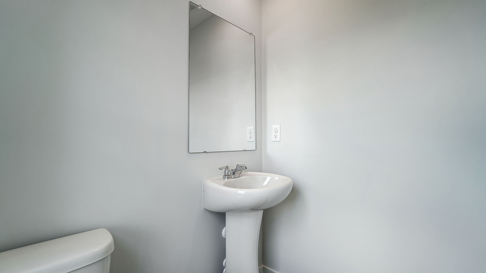 Half bath with standing sink and long mirror above.