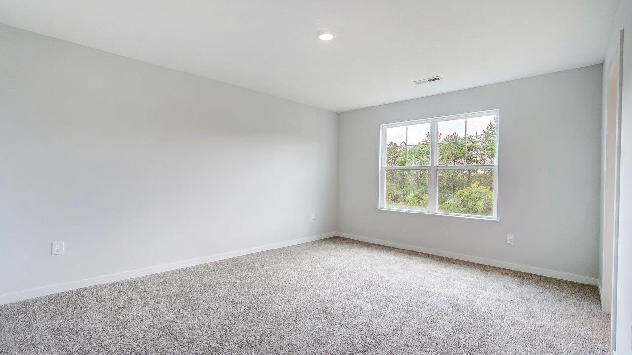 Primary bedroom with large windows and neutral walls.