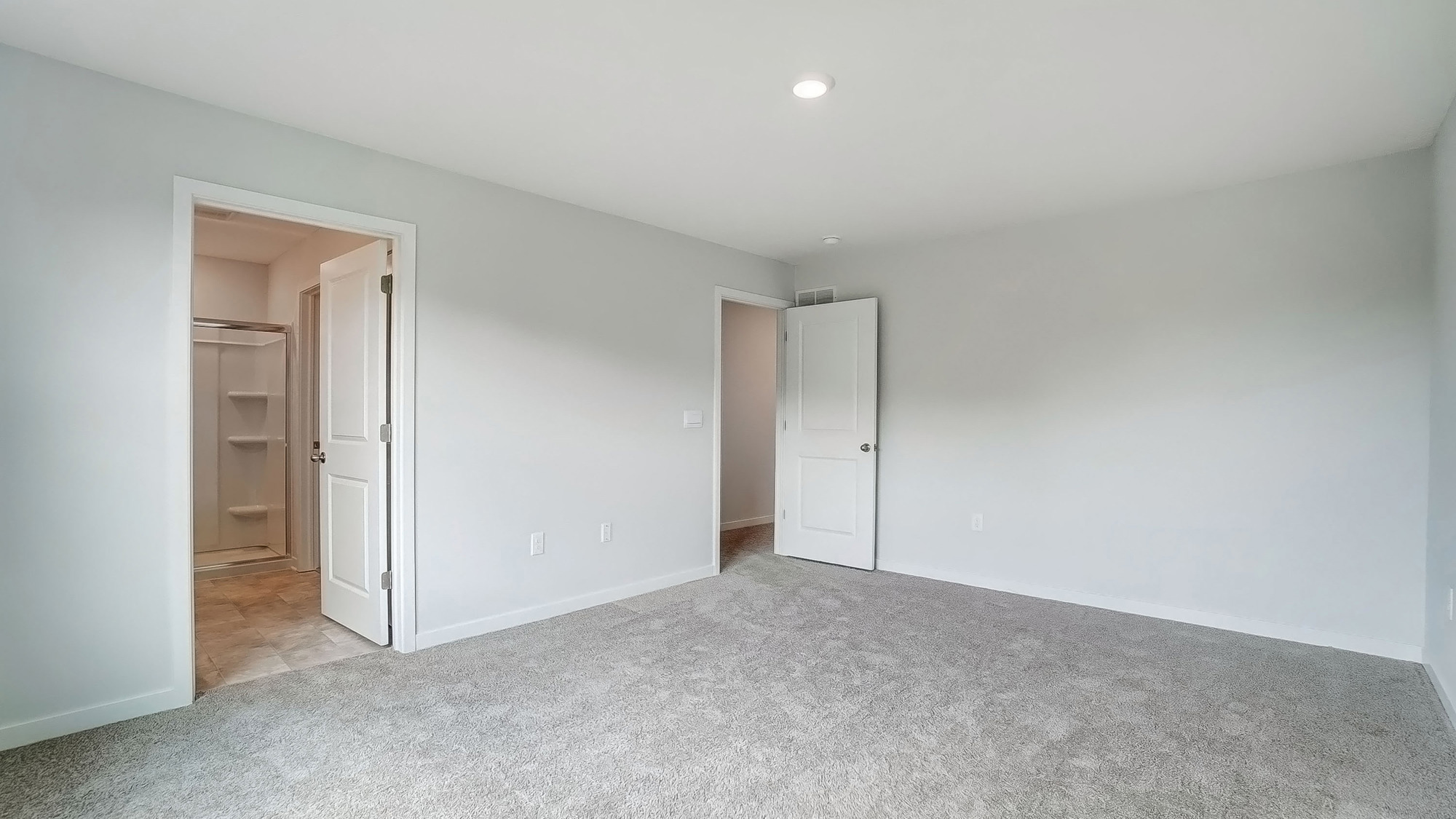 Primary bedroom with carpet, natural lighting, and a bathroom attached.