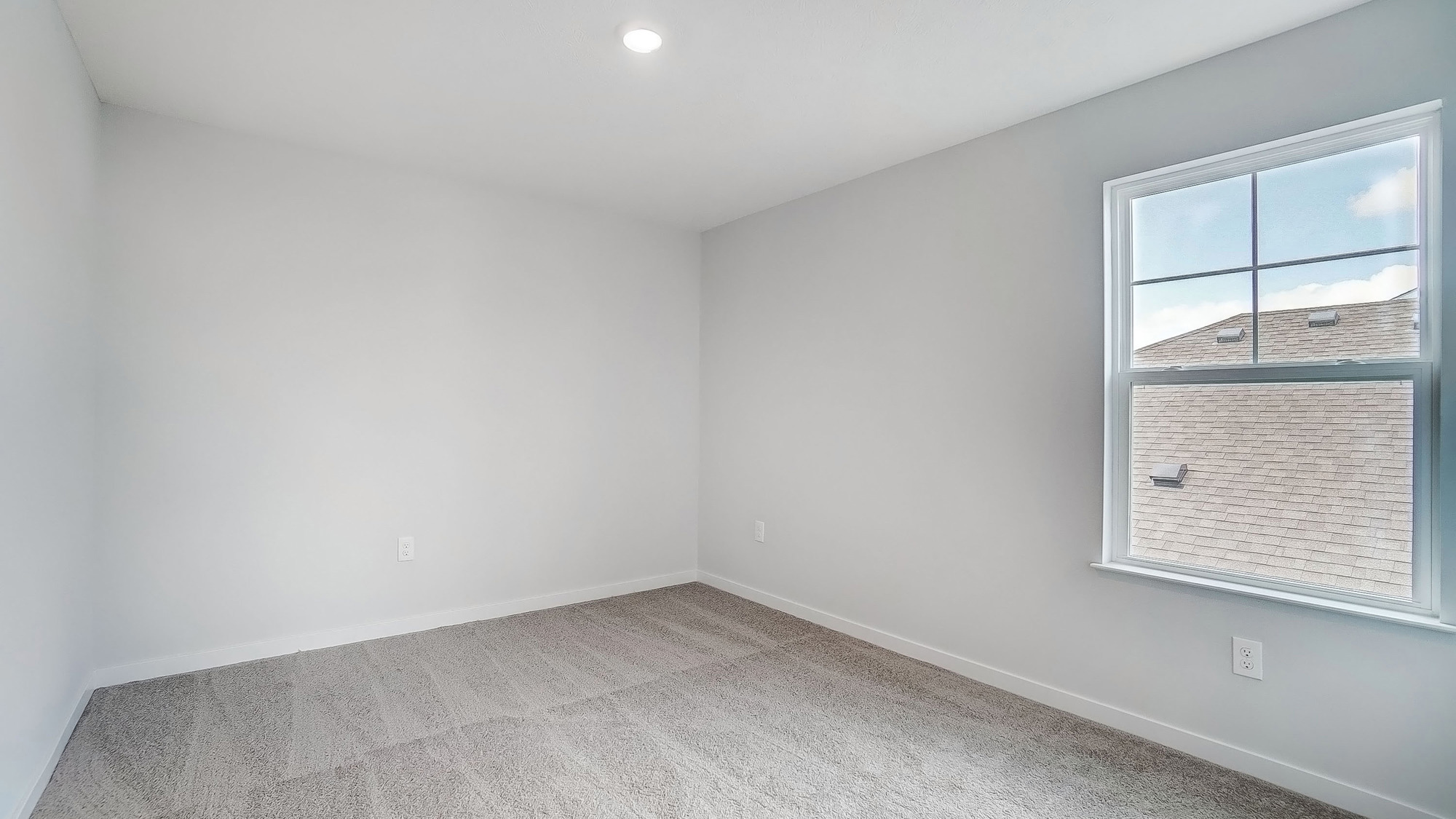 Bedroom with neutral walls, carpet, and a window.