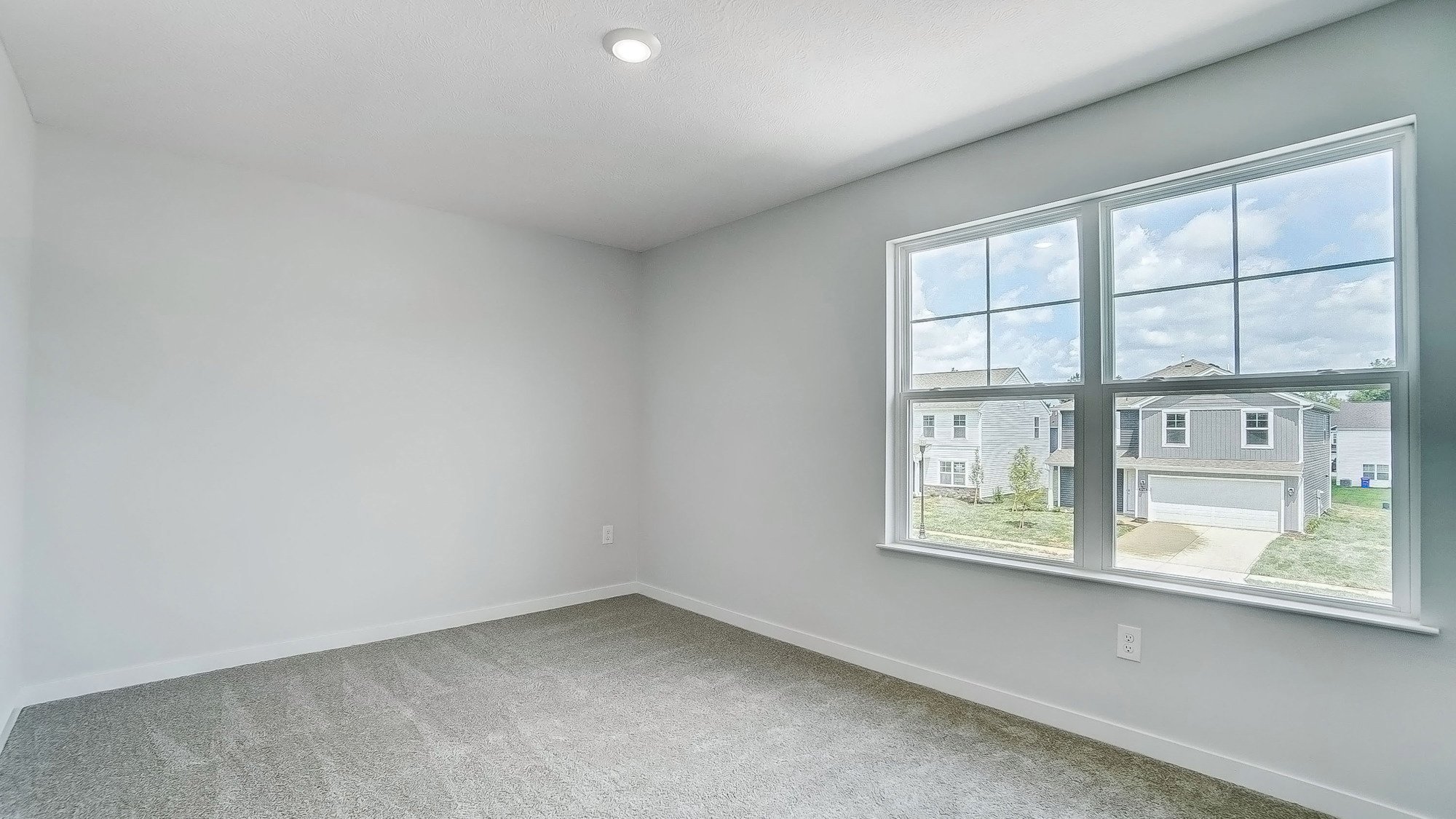 Bedroom with neutral walls, carpet, and a large window.