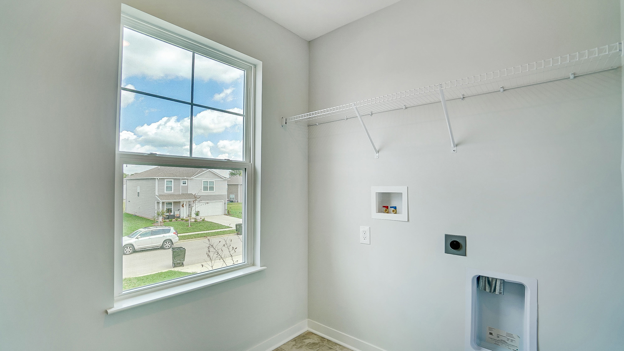 Laundry room with shelving above appliance hook ups and a window.