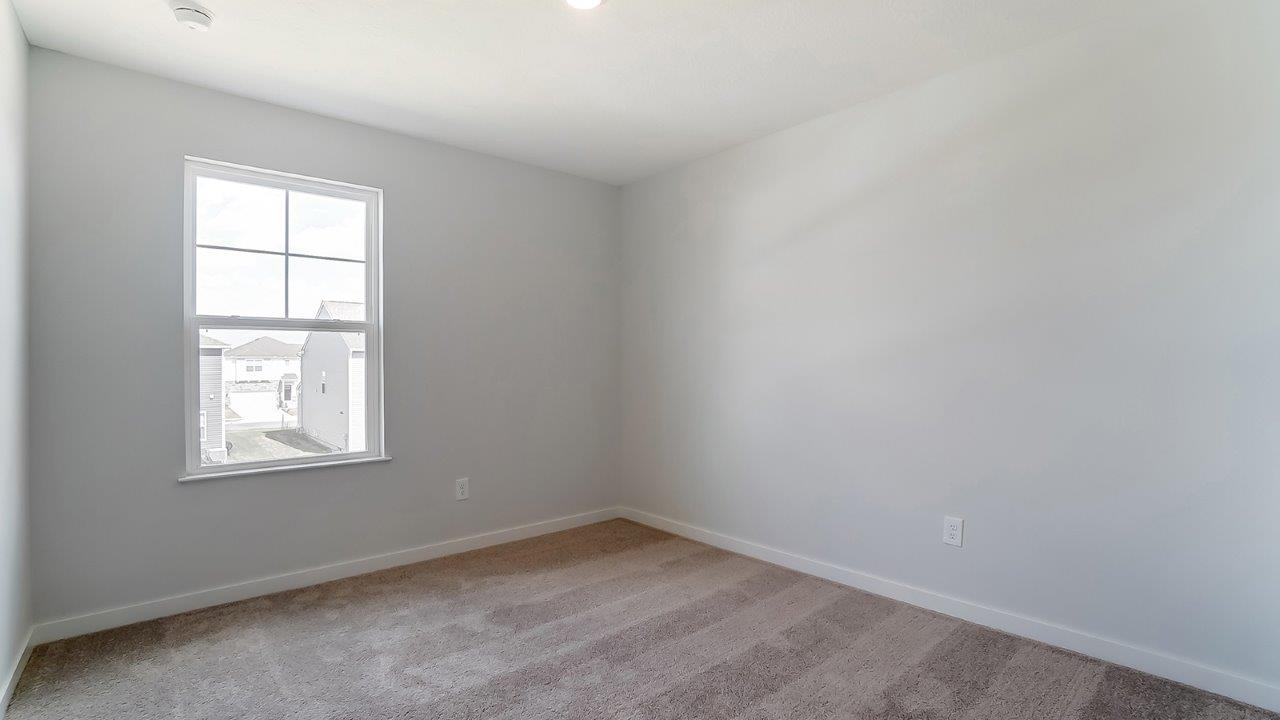 Bedroom with neutral walls, carpet, and a window.