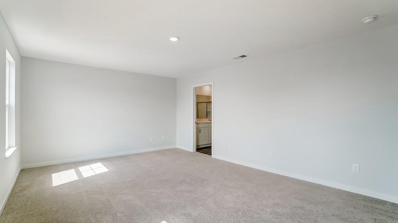 Primary bedroom with neutral walls, carpet, and natural lighting.