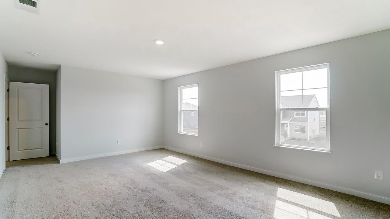 Primary bedroom with neutral walls, carpet, and windows