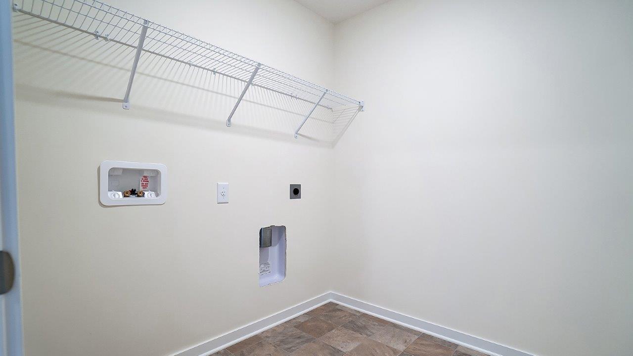 Laundry room with shelving above appliance hook ups.