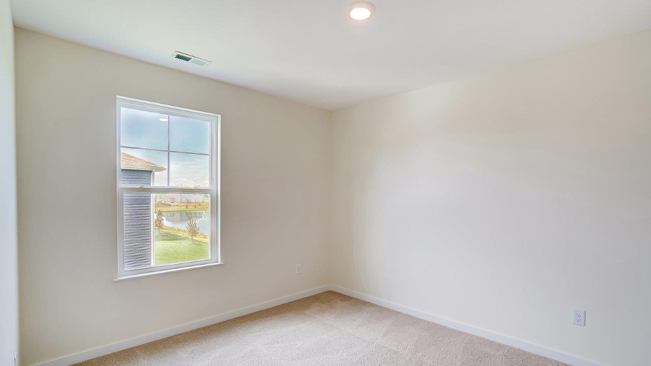 Bedroom with neutral walls, carpet, and a window.
