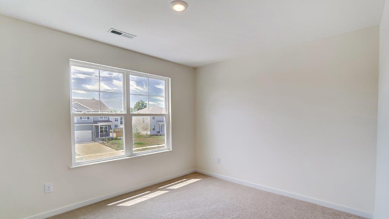 Bedroom with neutral walls, carpet, and a window.