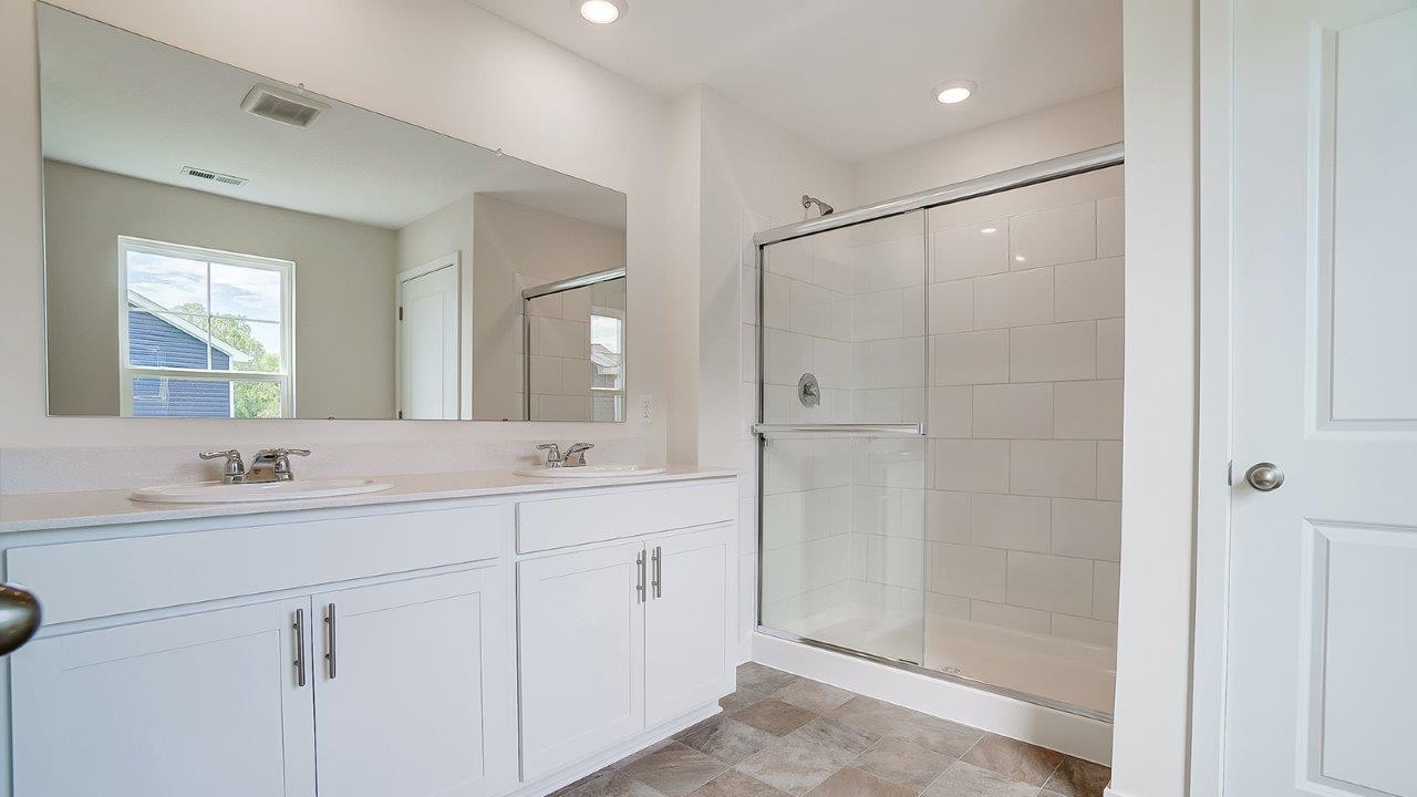 Bathroom with dual sinks and a walk in shower.