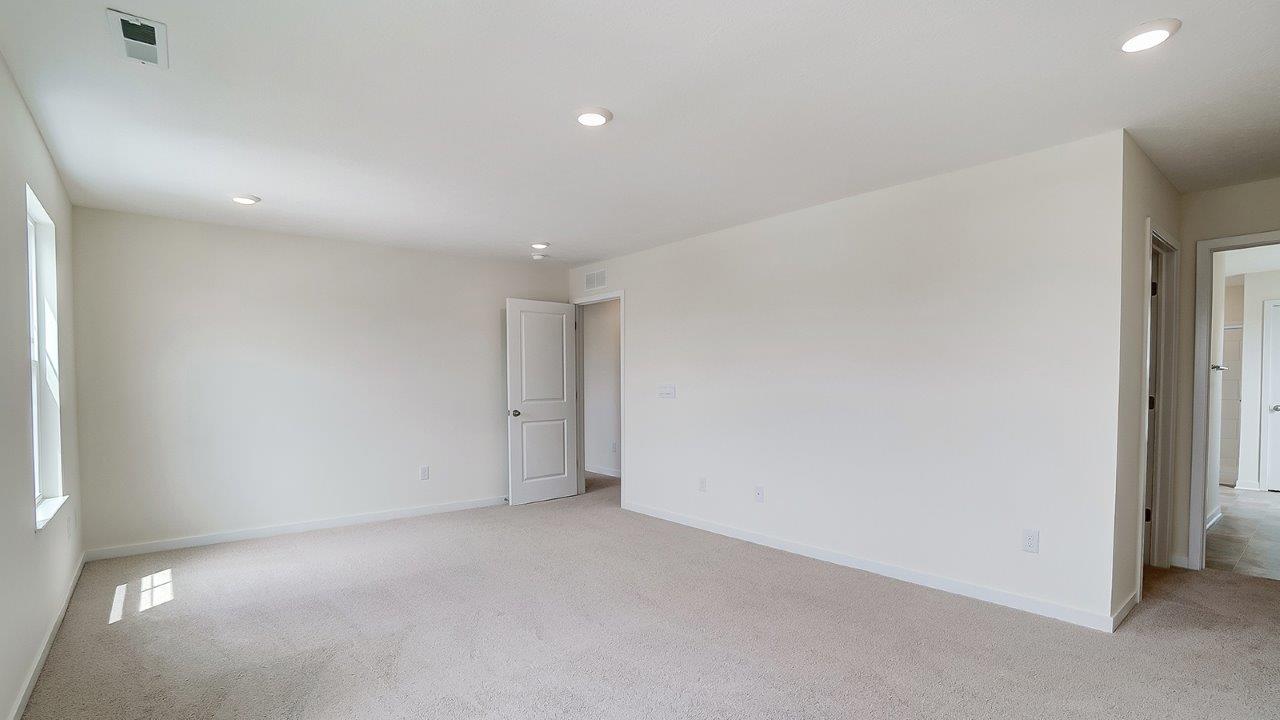 Primary bedroom with carpet, natural lighting, and a bathroom attached.