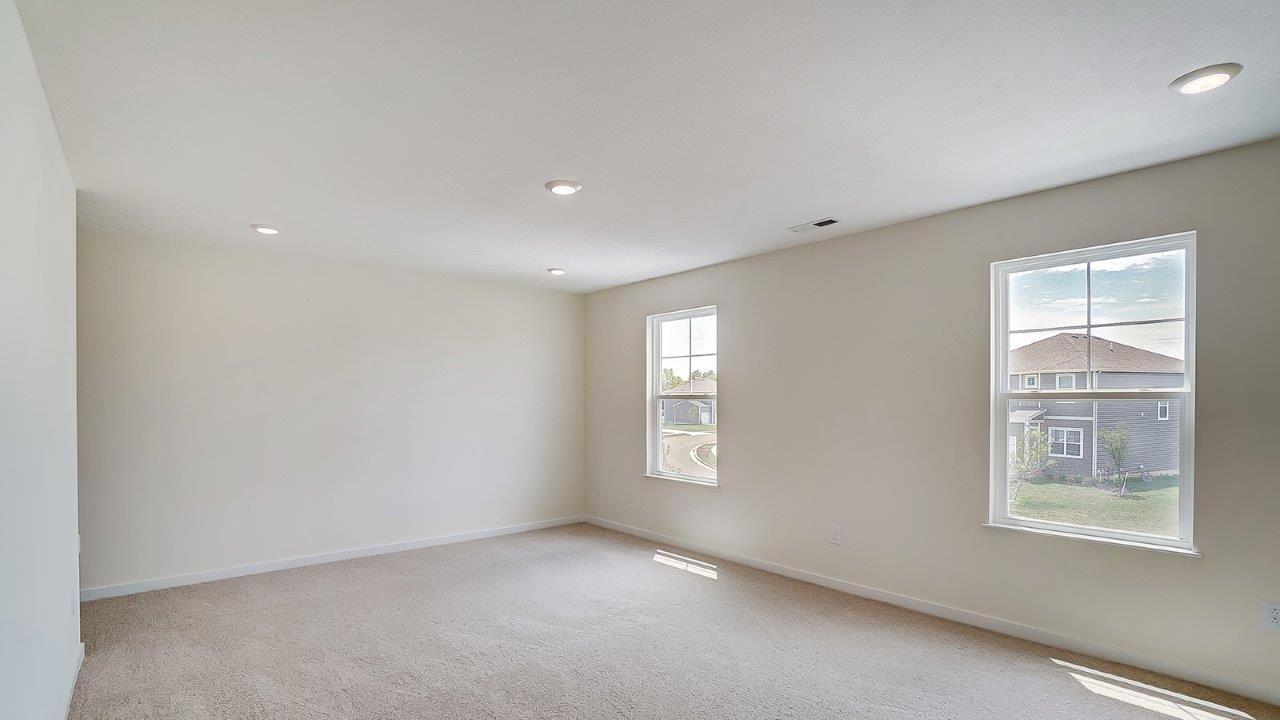 Primary bedroom with large windows and neutral walls.