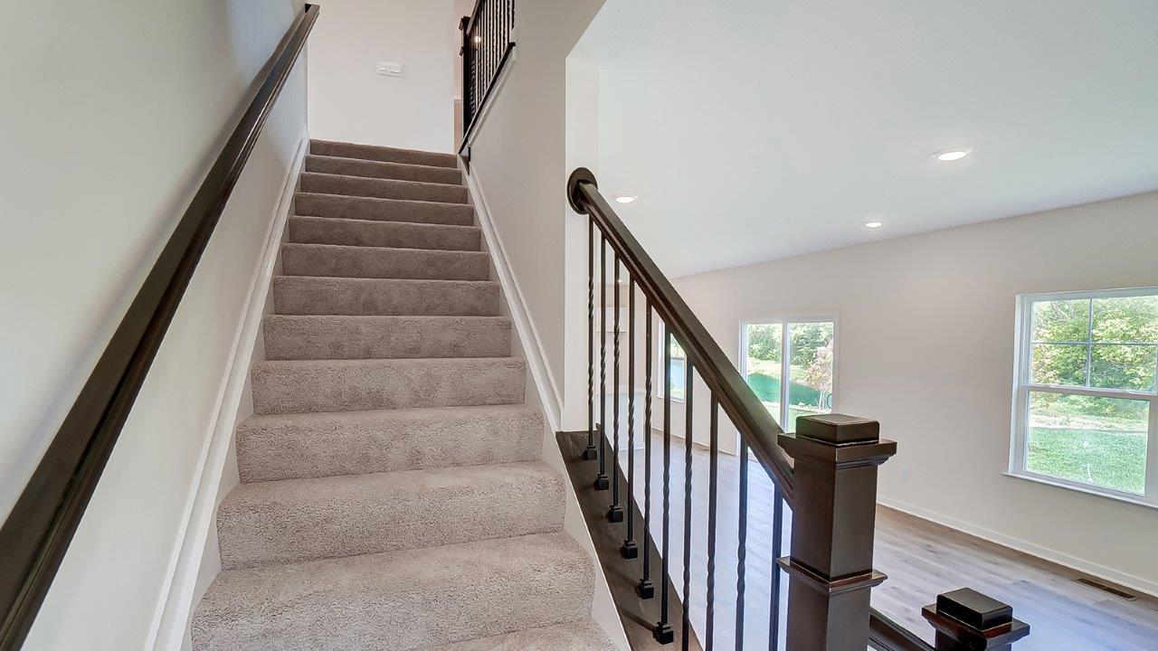 Staircase with carpet and dark railing.