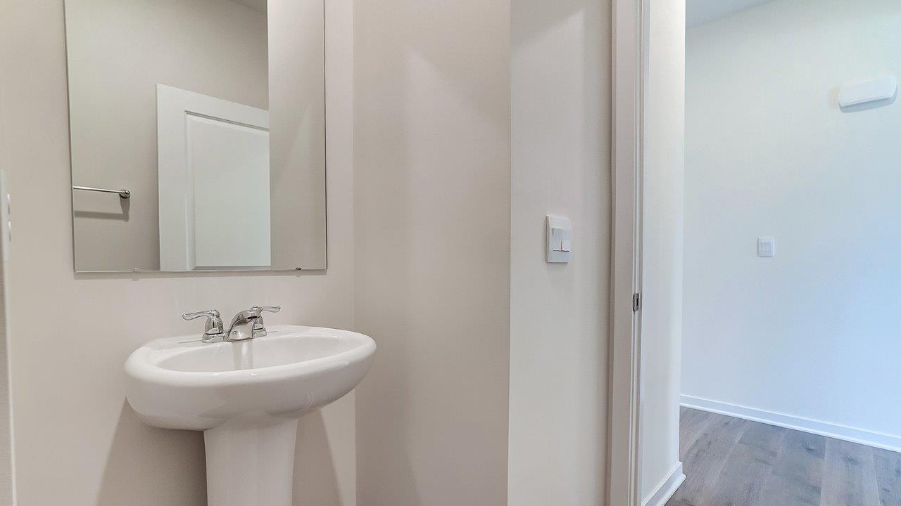 Half bath with standing sink and long mirror above.