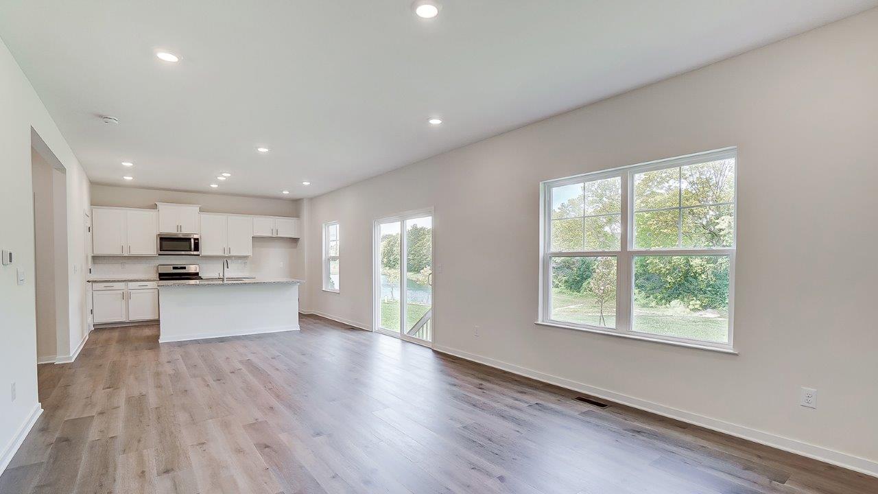 Main living area with clean flooring and natural light connecting to kitchen.