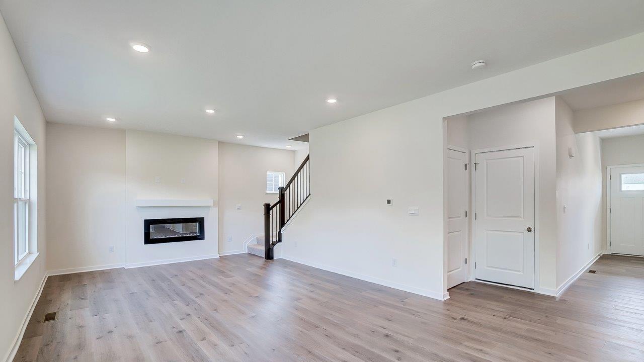 Main living area with clean flooring and natural light featuring a fireplace.