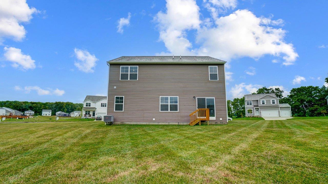 View of the rear of the home with open grassy area.