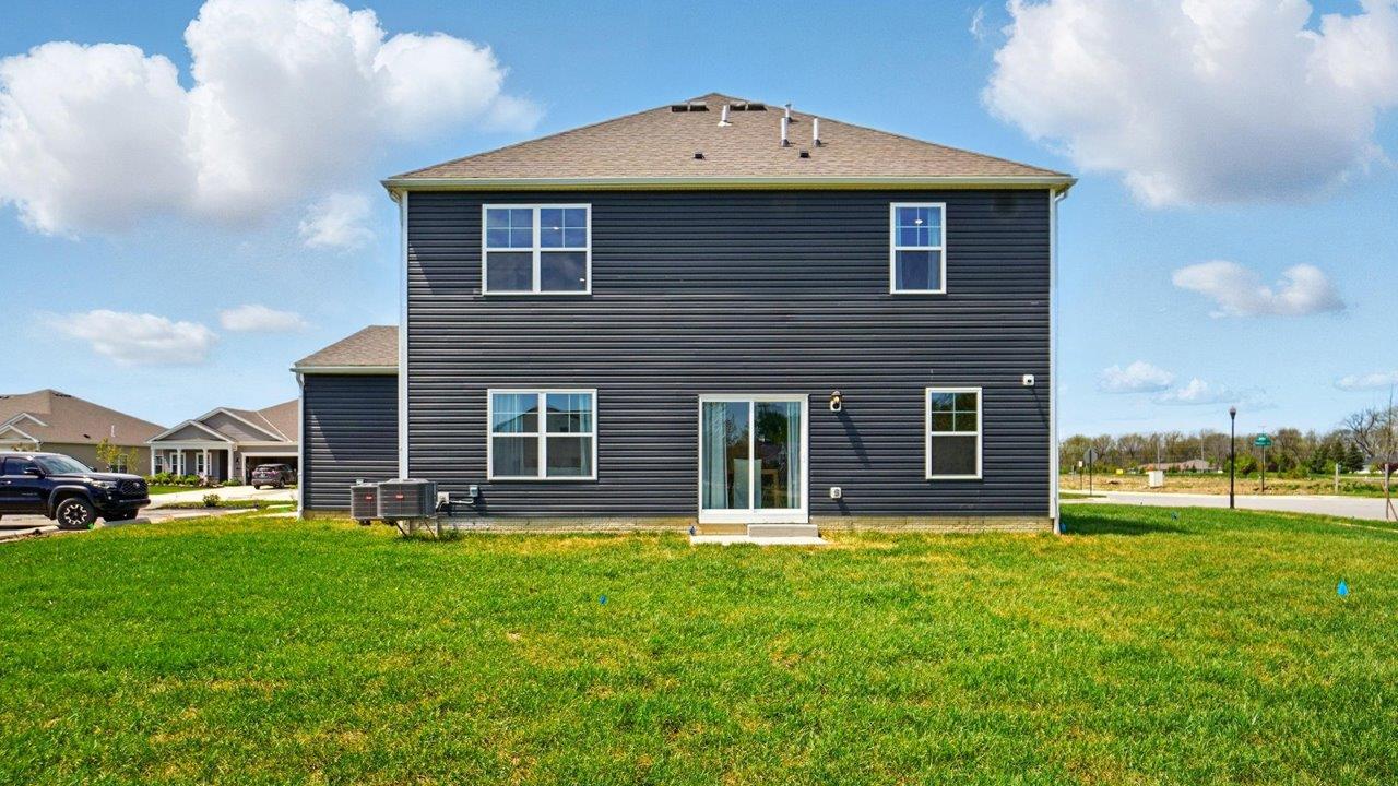 View of the rear of the home with open grassy area.
