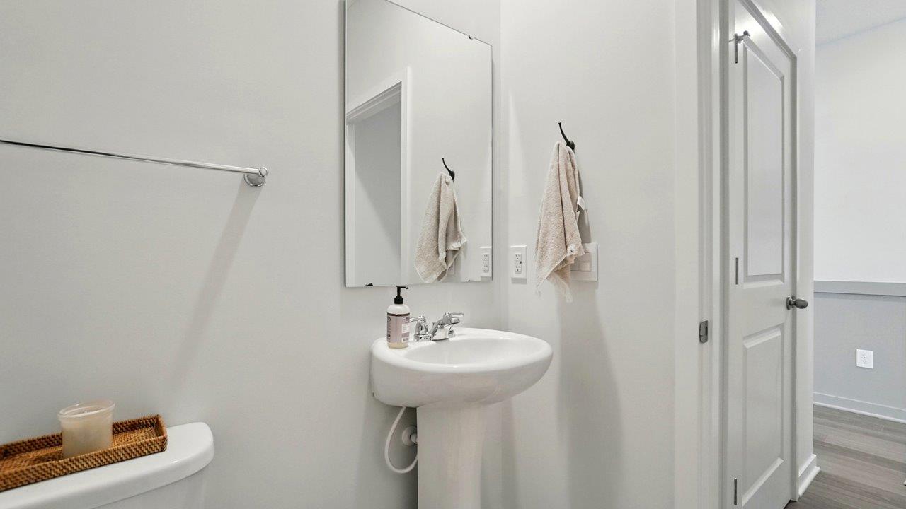 Half bath with standing sink and long mirror above.
