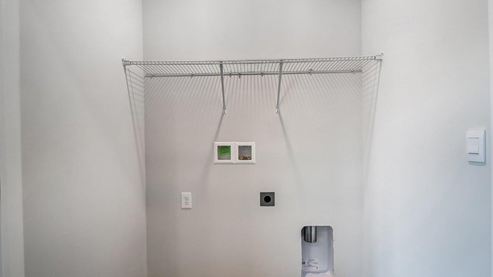 Laundry room with shelving above appliance hook ups.