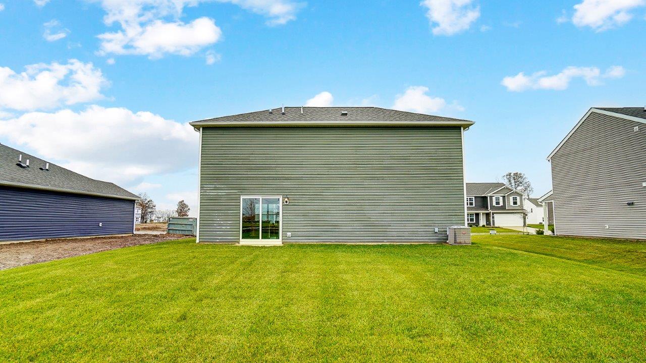 View of the rear of the home with open grassy area.