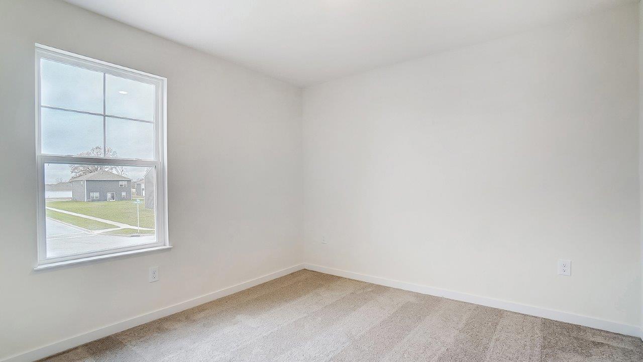Bedroom with neutral walls, carpet, and a window.