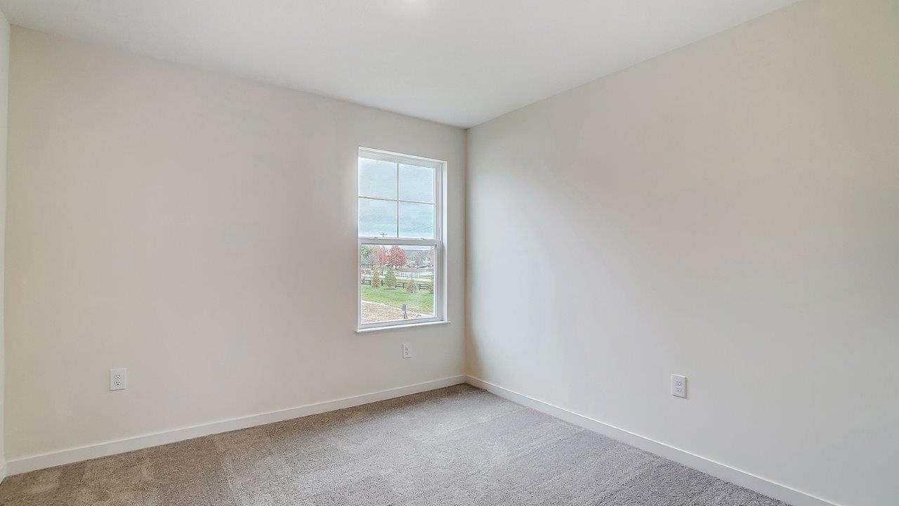 Bedroom with neutral walls, carpet, and a window.