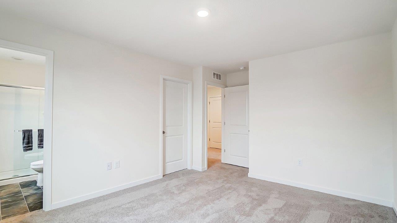 Primary bedroom with carpet, natural lighting, and a bathroom attached.