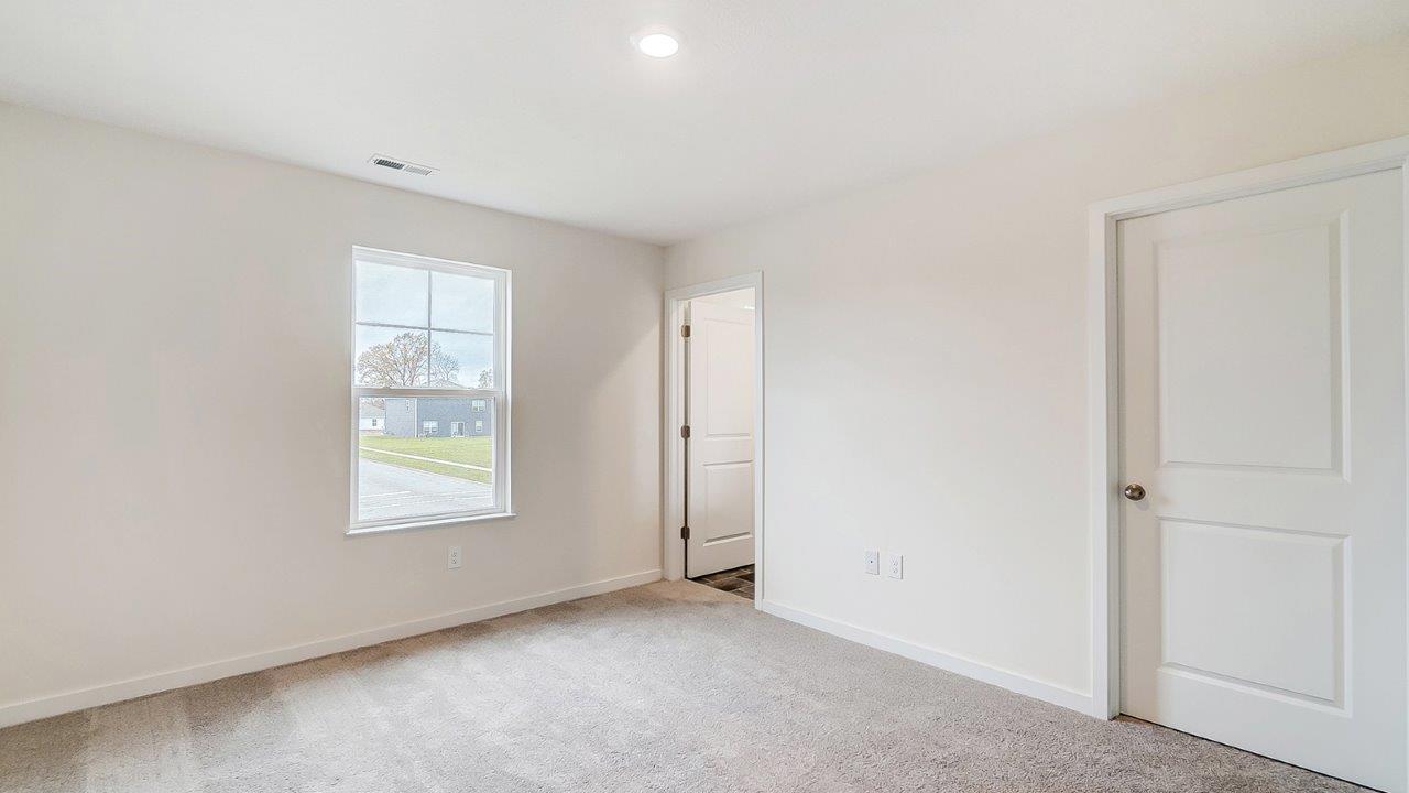 Primary bedroom with neutral walls, carpet, and windows