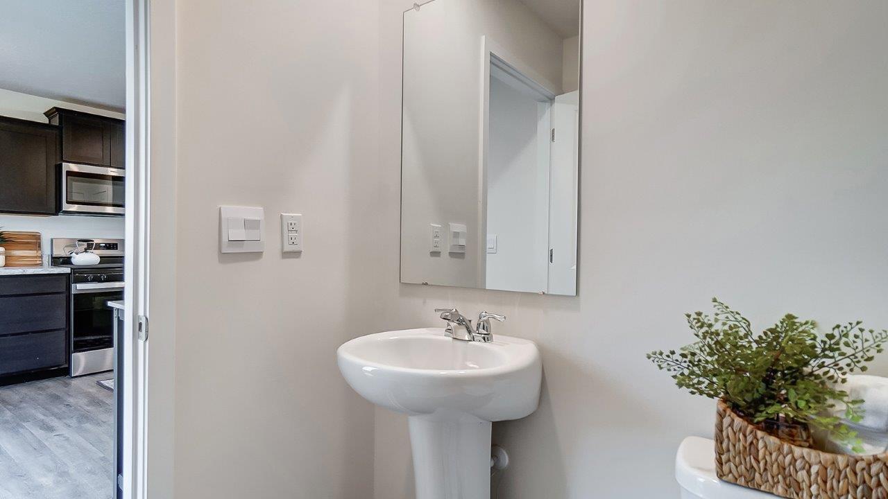 Half bath with standing sink and long mirror above.