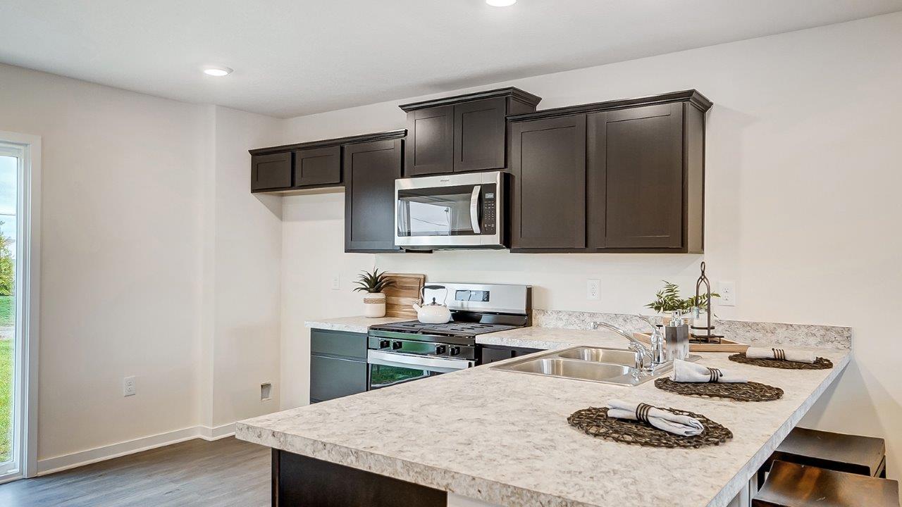 Kitchen showcasing new stainless steel appliances, cabinets, and countertops.