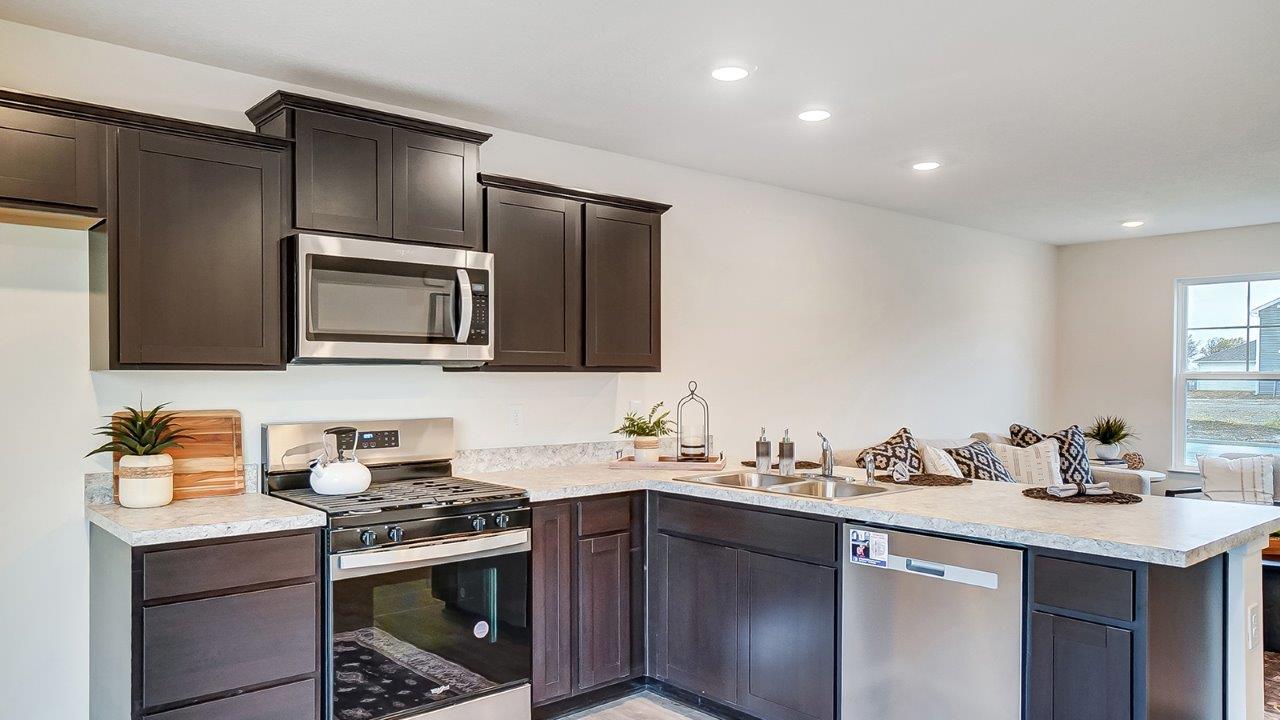 Kitchen featuring dark cabinets, new stainless steel appliances, and textured countertops.