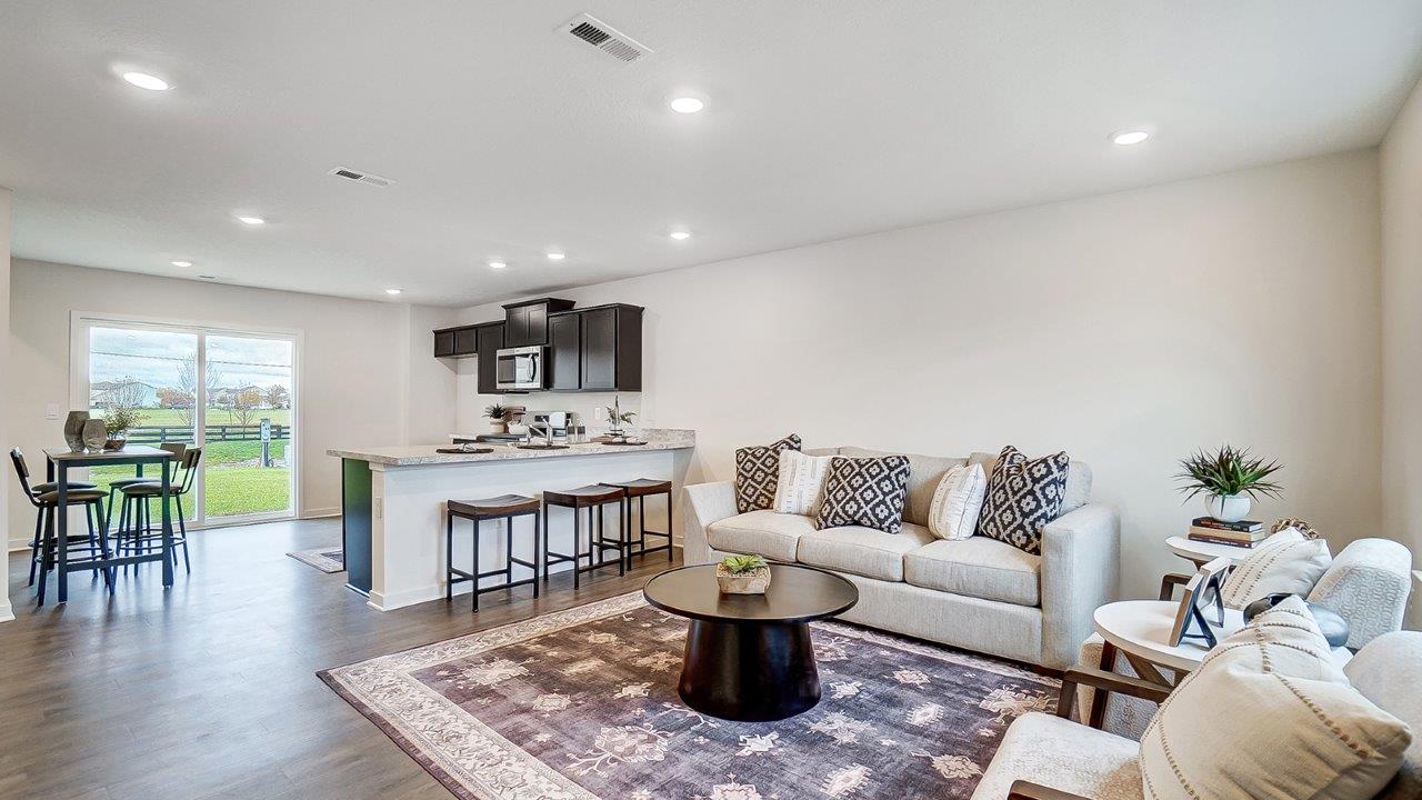 Main living area with clean flooring and natural light connecting to kitchen.